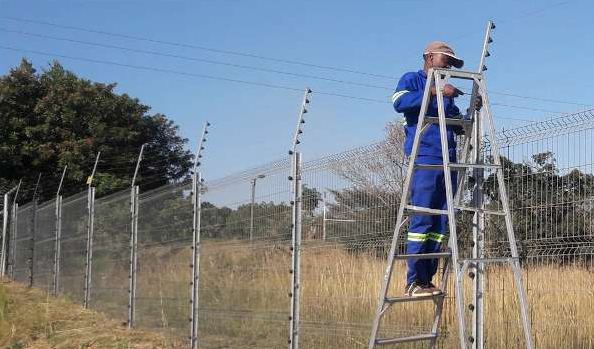 Technician on a ladder installing an electric fence